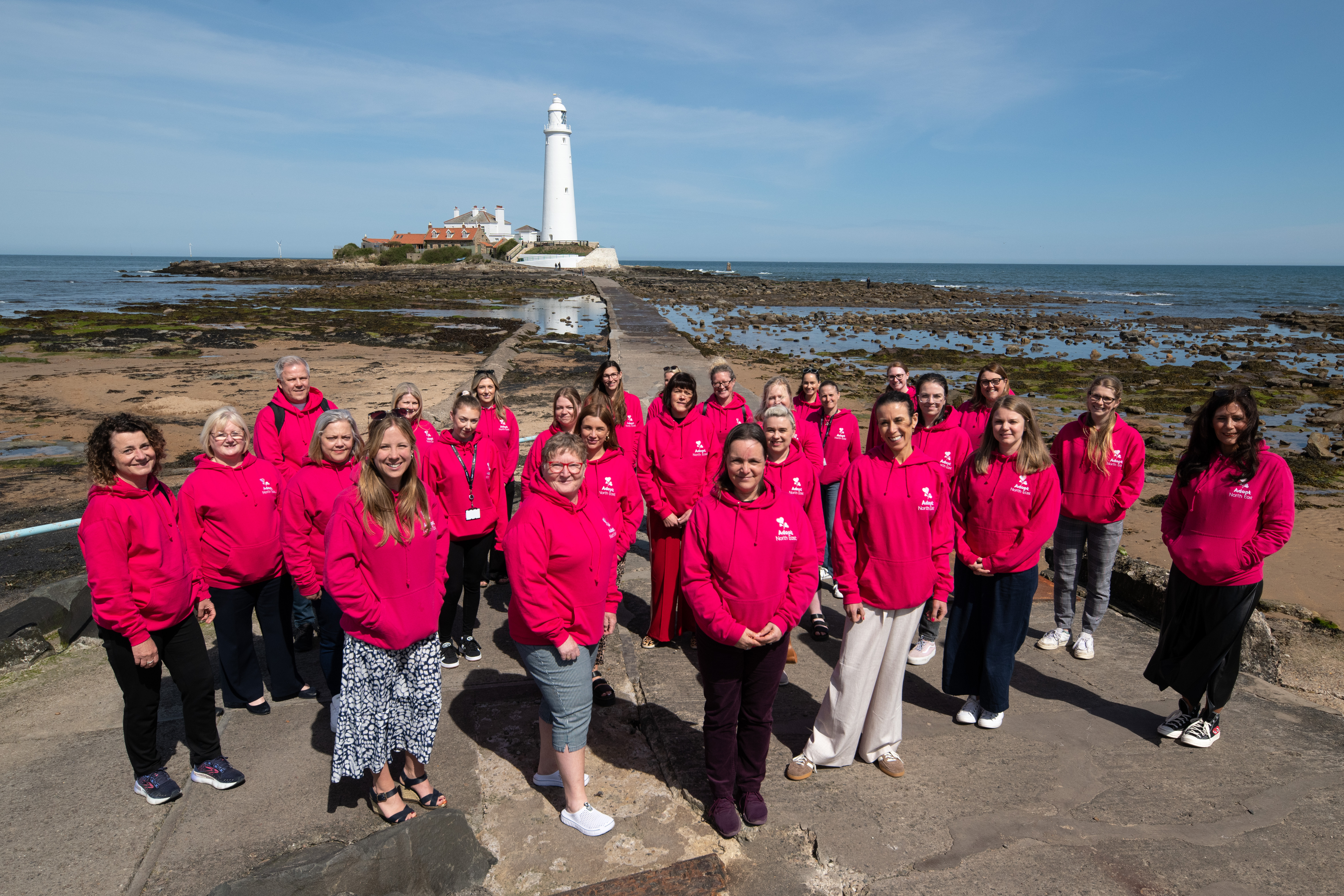 Adopt North East colleagues in pink Adopt NE jumpers in front of St Mary's Lighthouse