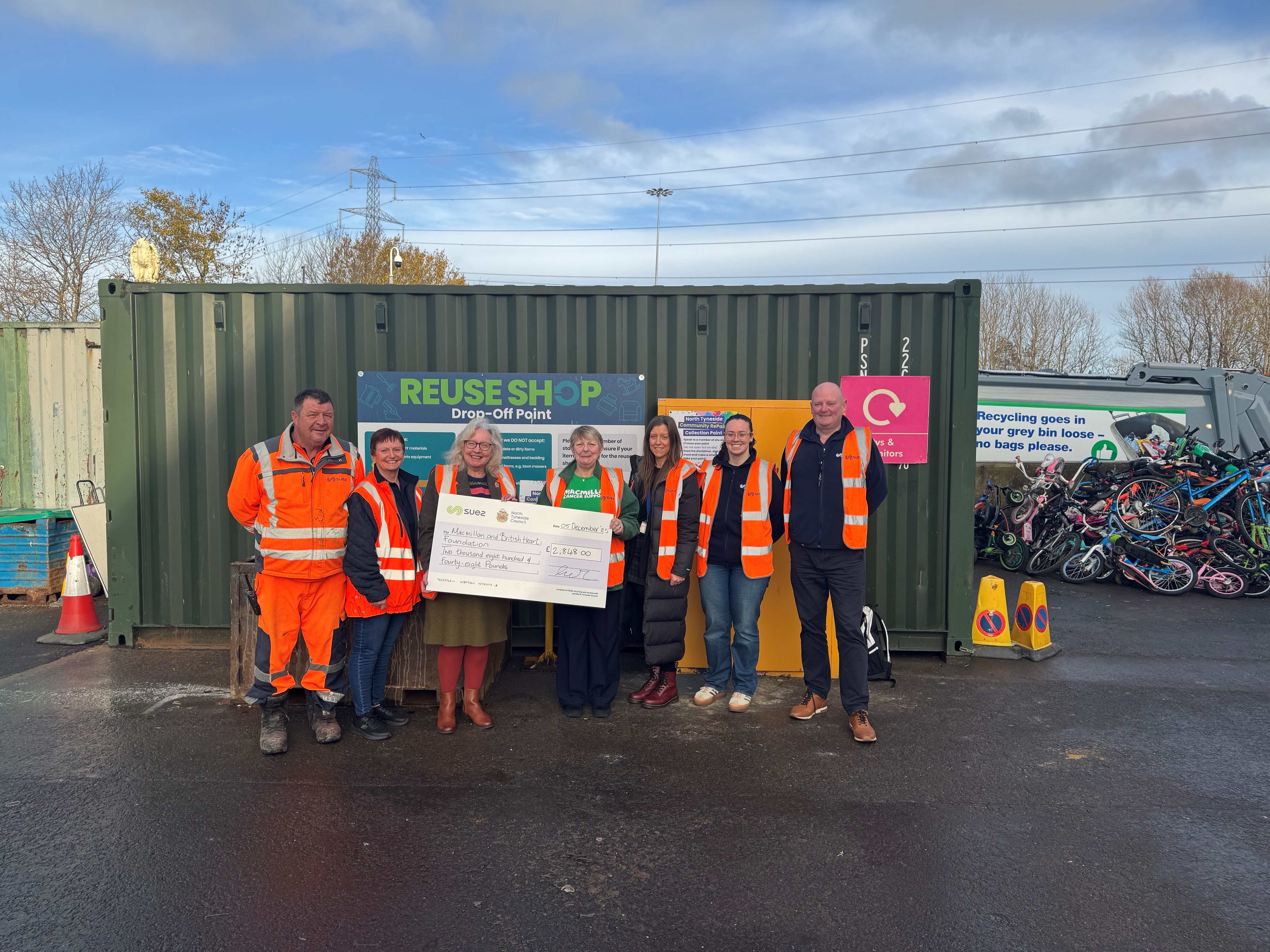 Group of people with charity cheque outside reuse container at North Tyneside HWRC