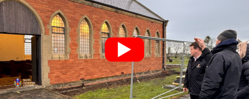people looking and pointing at a brick building in a cemetery