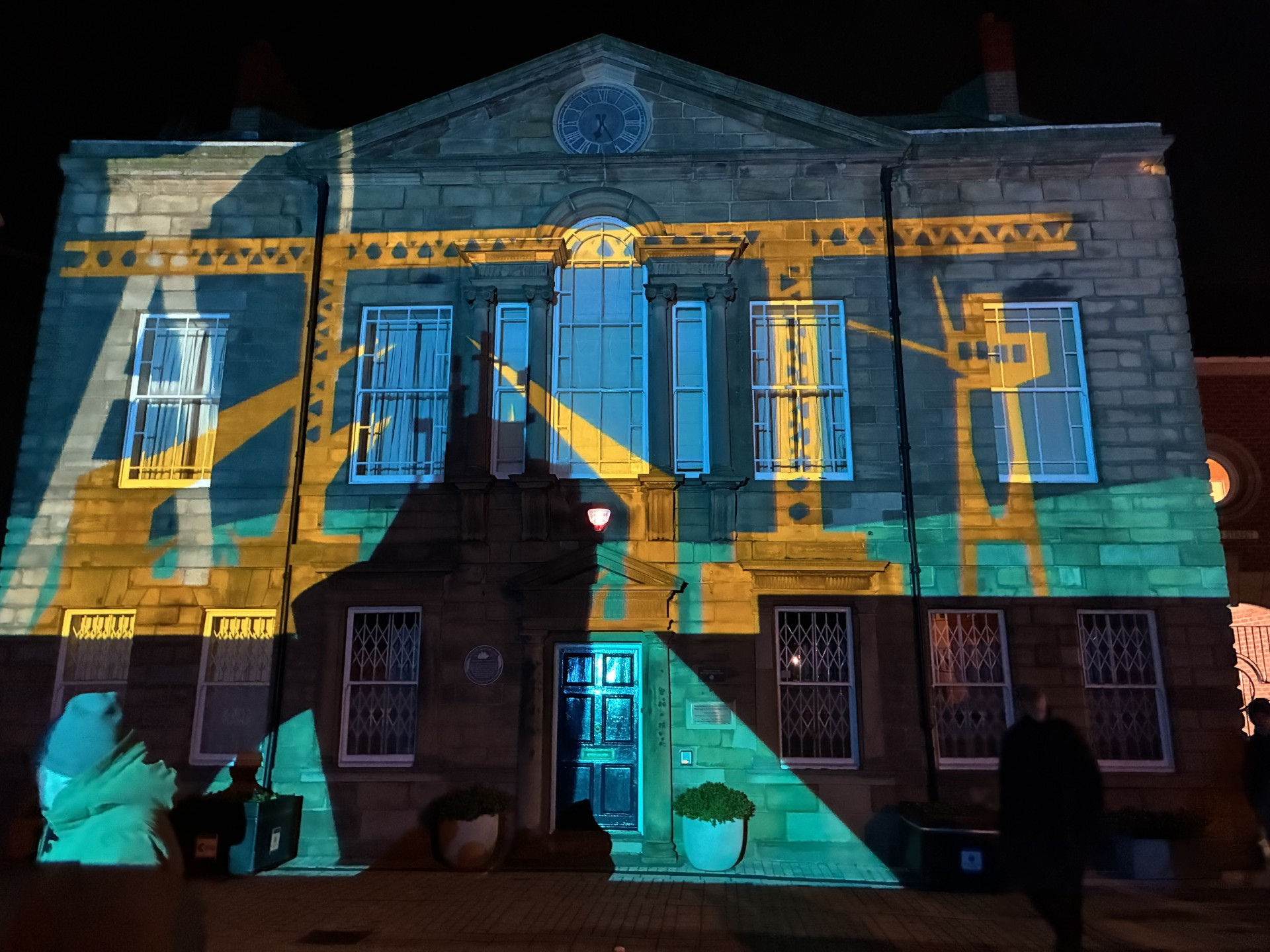 Lights shining on a building showing cranes and offshore machinery