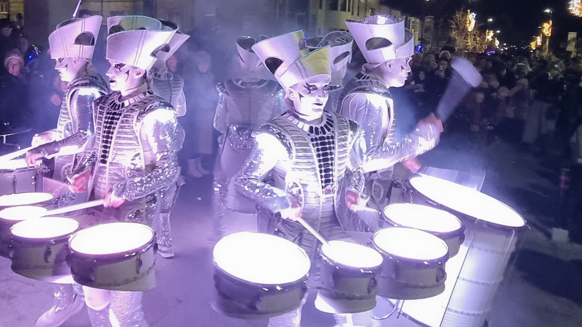Drummers lit up and dressed in silver costumes