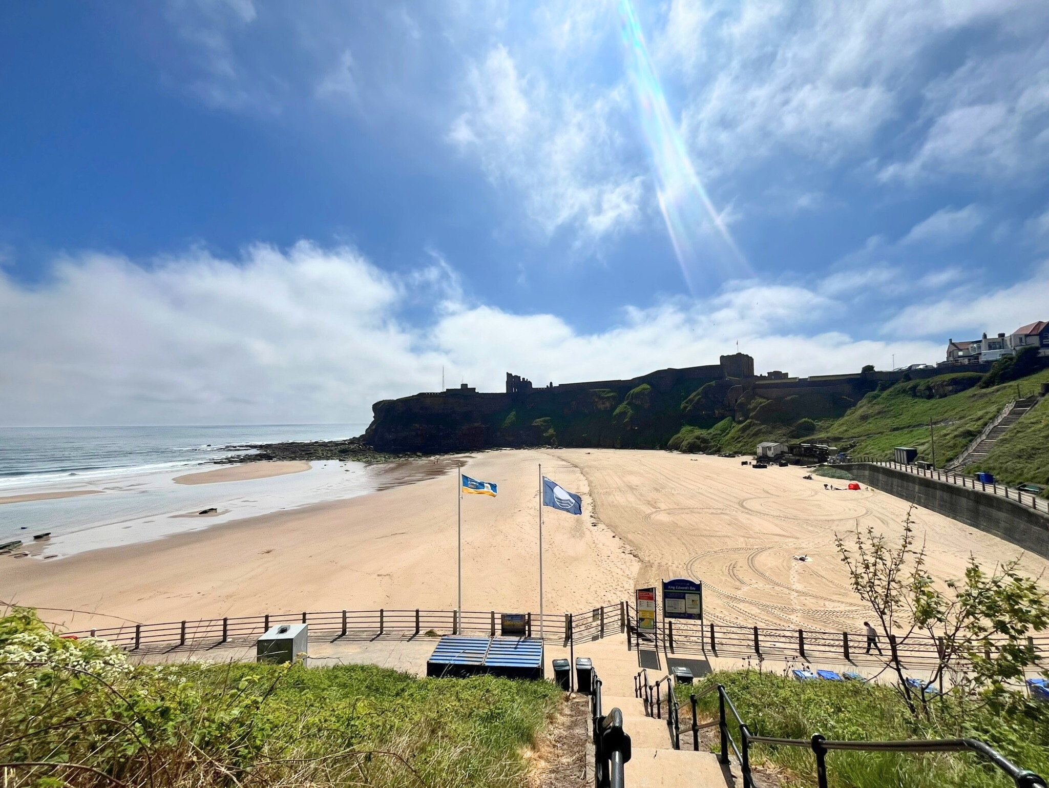 Beach in North Tyneside with two blue flags in the foreground