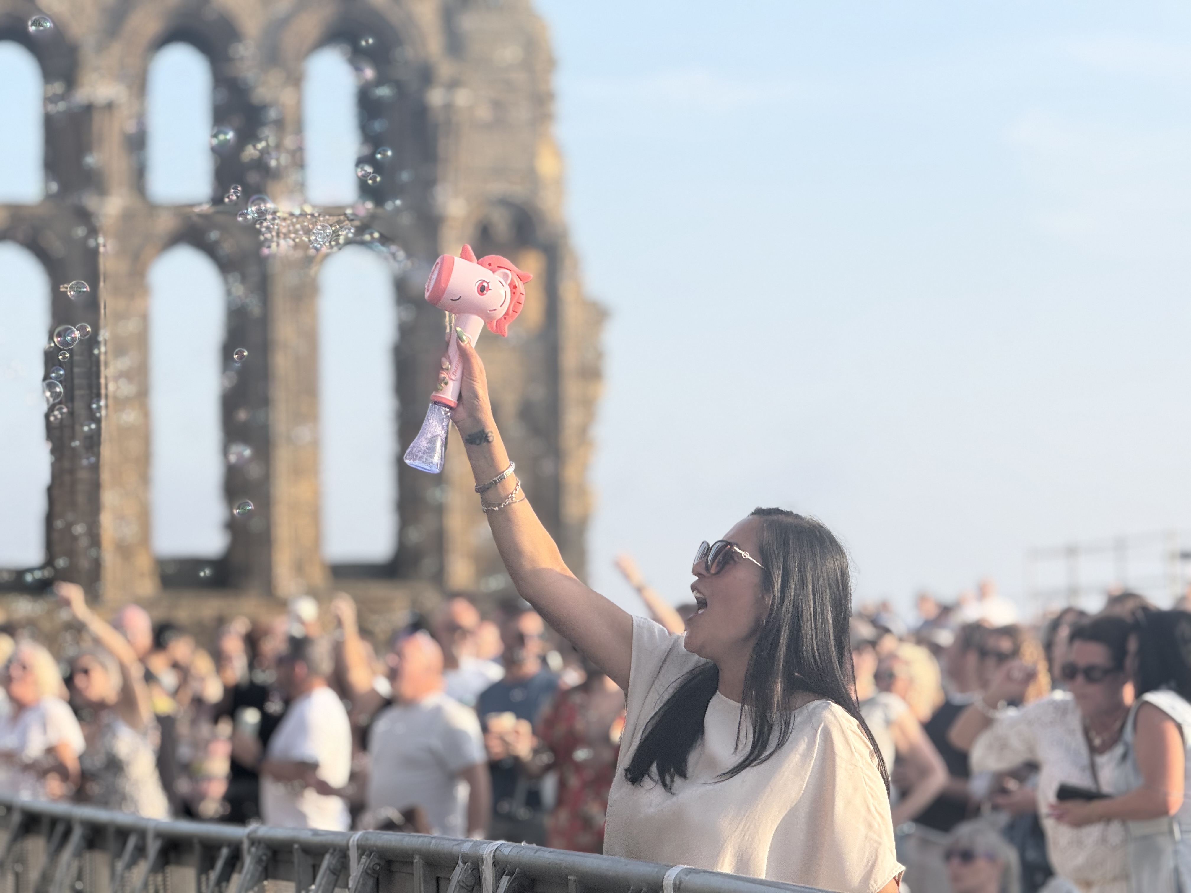 A pink, Unicorn Bubble Machine in action, with Tynemouth Priory in the backround