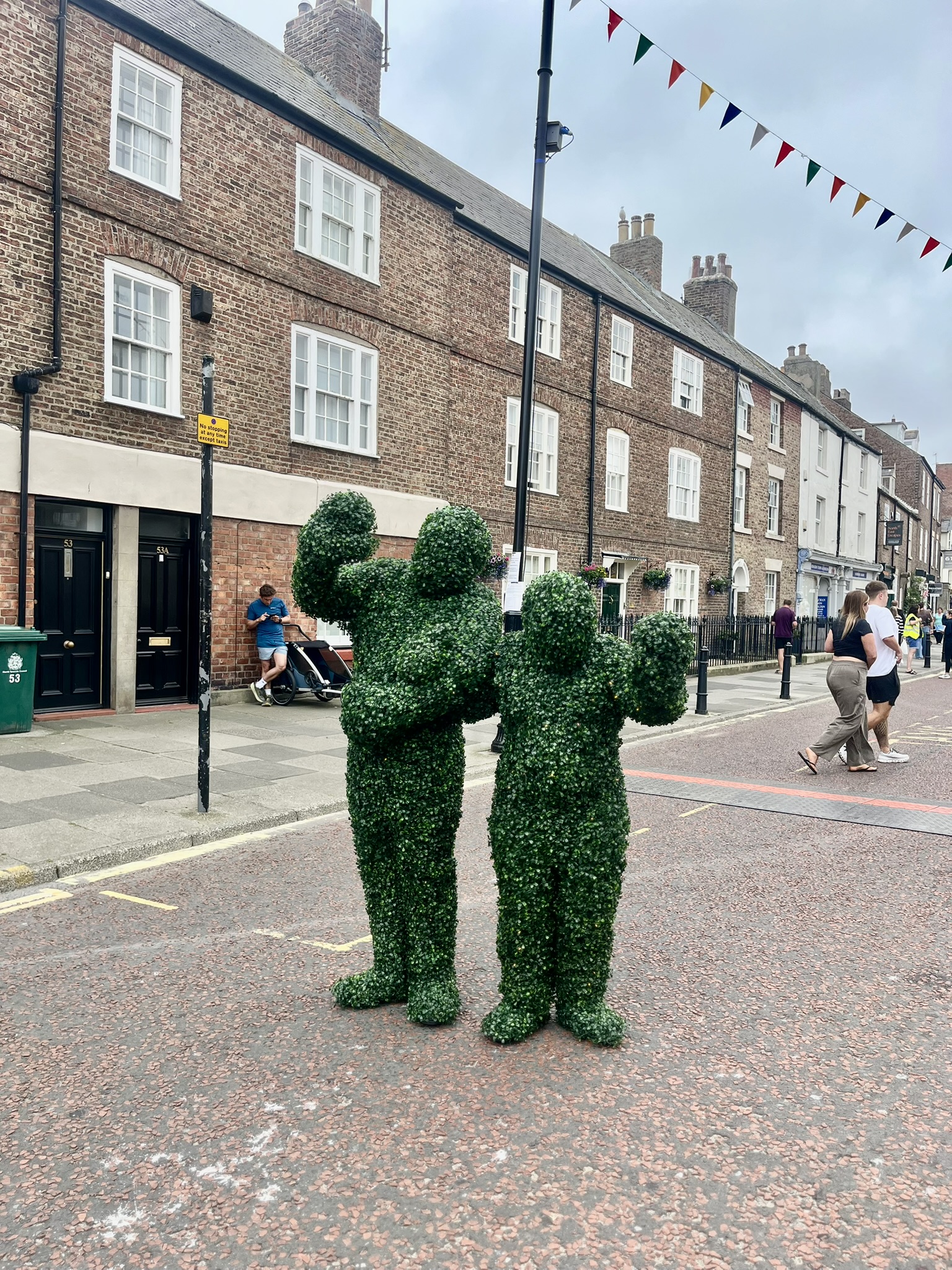 Two waving bushes stand below the bunting, stringed streets.