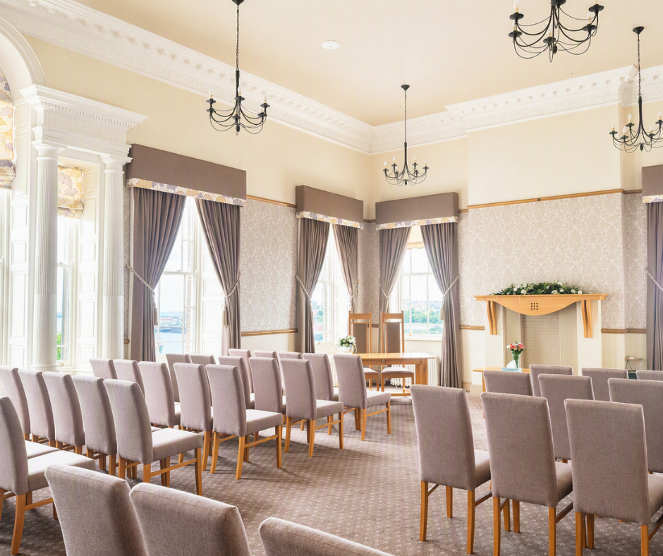 A neautral brightly it room with rows of chairs lined up for a wedding