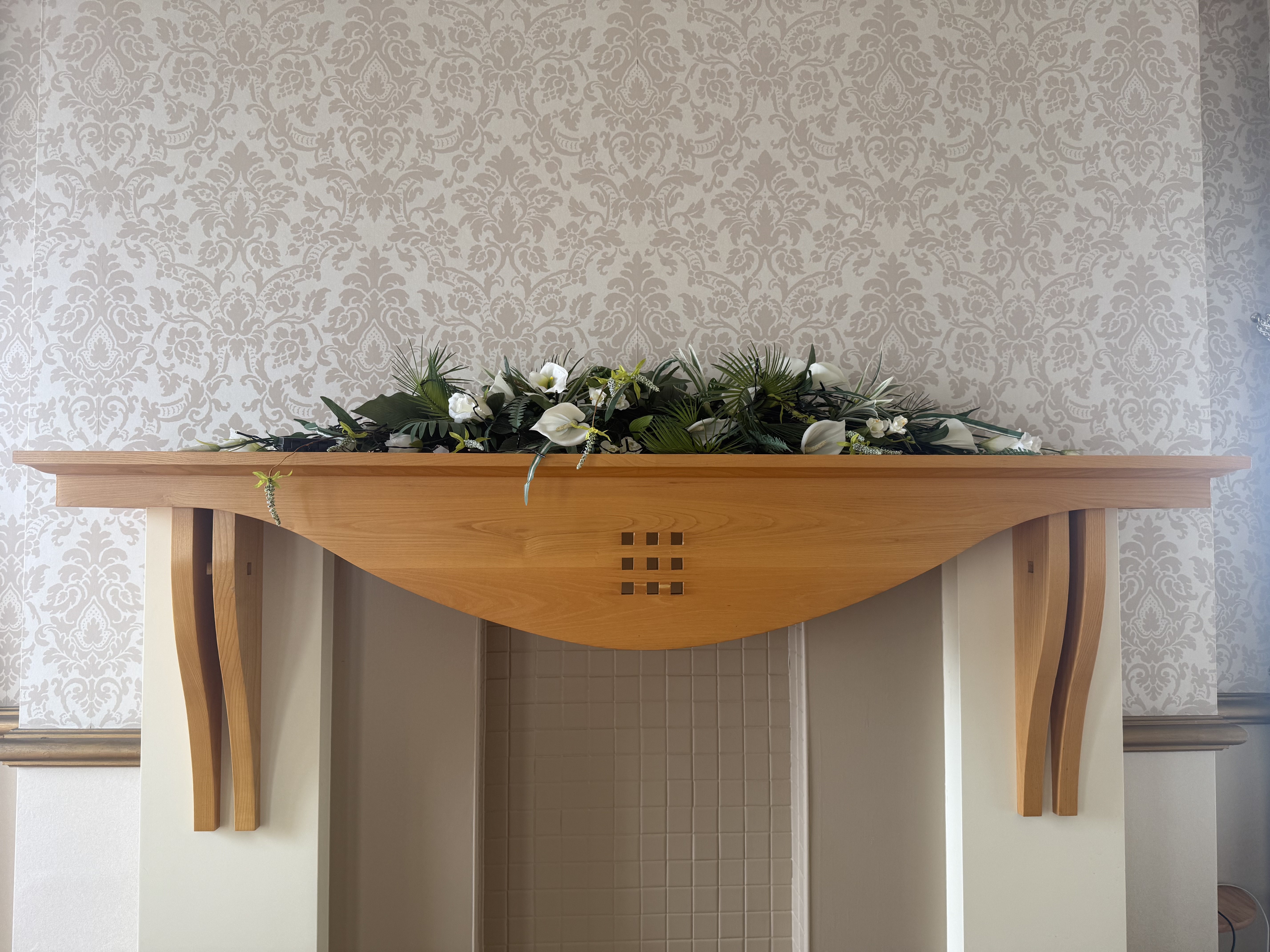 A mantlepiece with a display of white flowers decorating it
