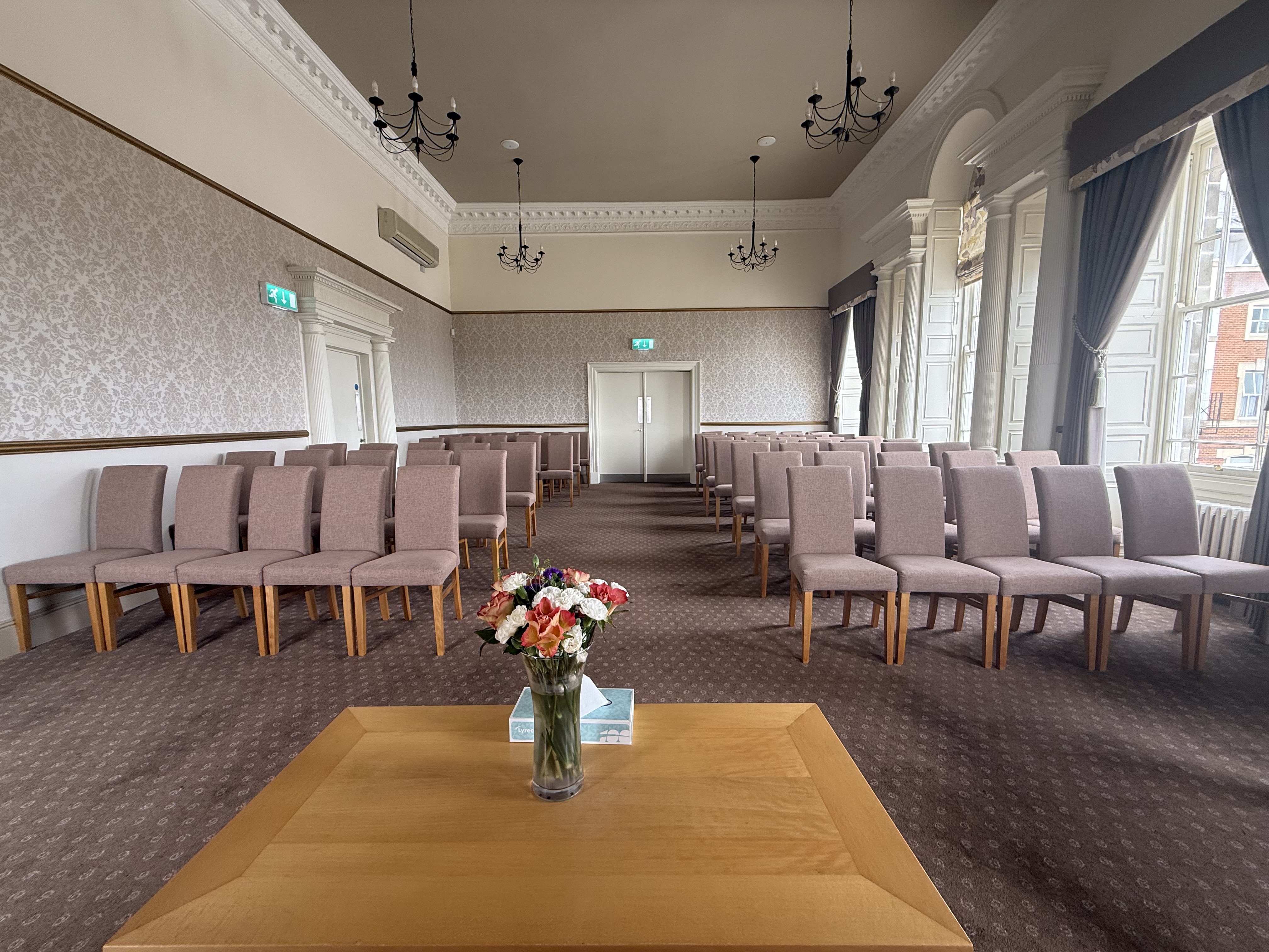 A room with a table in the foreground set up for a wedding