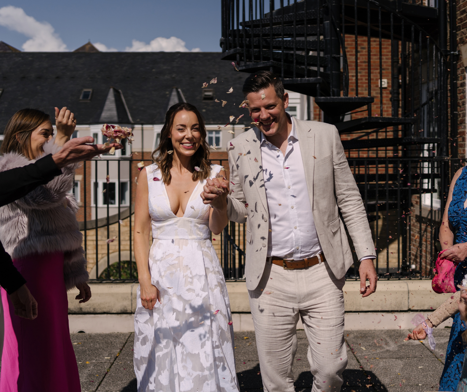 A bride and groom walk through a group of people, confetti is thrown over them