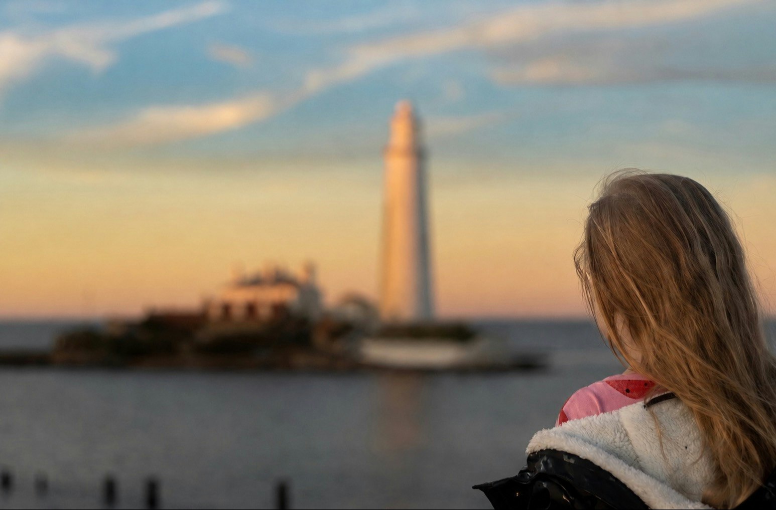 Image shows a young girl watching the sunset at St Mary's Lighthouse 