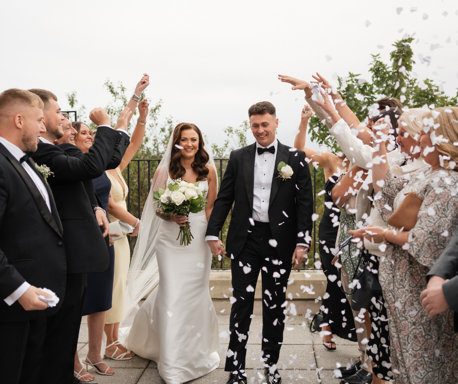 A bride a groom walk through a crowd of people
