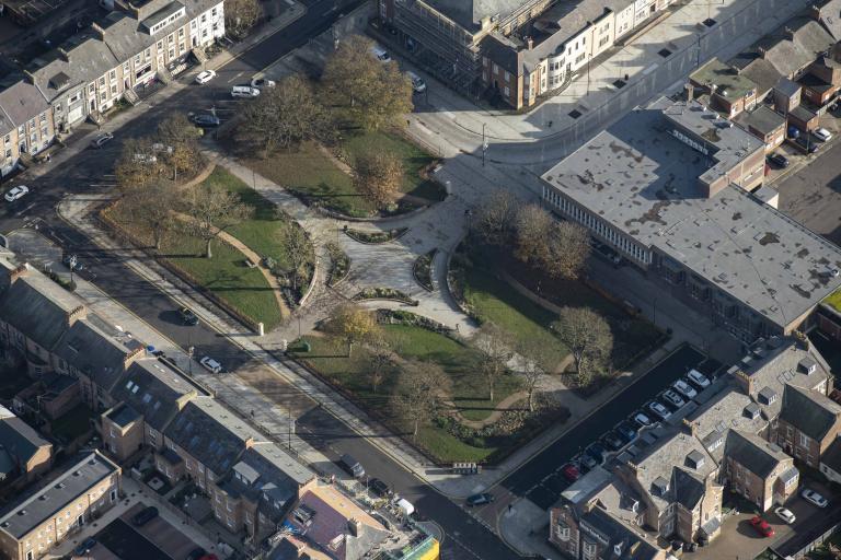 An aerial image of Northumberland Square after the restoration showing a grid of paths with grass, flowerbeds and trees in between and roads and buildings on all sides 