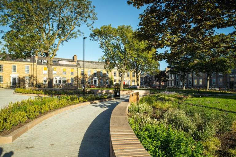 Northumberland Square with a path leading into the distance with flowerbeds on either side and trees on a sunny day