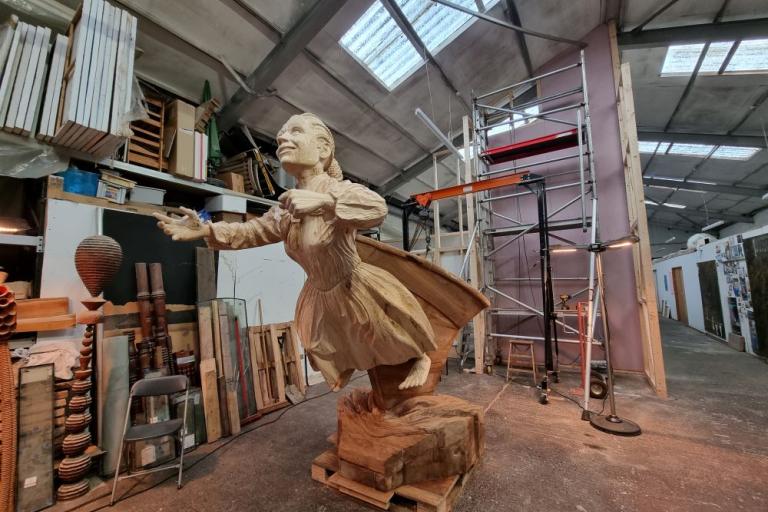 A wooden sculpture of Mary Ann Macham in an artist's studio