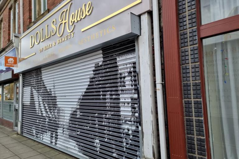 A colour photo of a beauty salon with a vinyl of a black and white photo covering its shutters