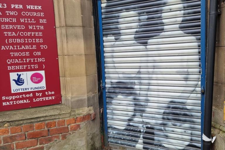 A colour photo of the memorial hall in Wallsend with a vinyl of a black and white photo covering its shutters