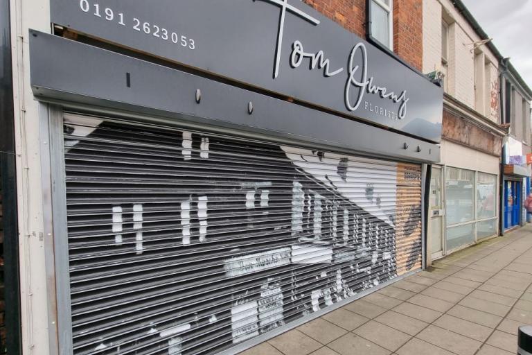A colour photo of a florist shop with a vinyl of a black and white photo covering its shutters