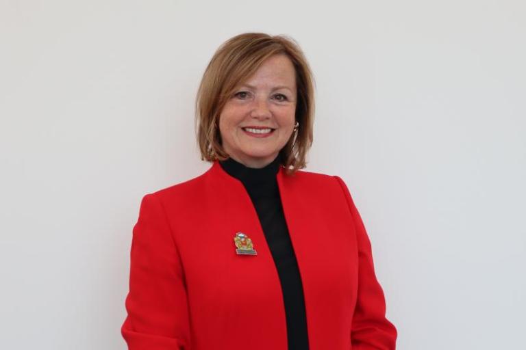 Image of Karen Clark wearing a red jacket and North Tyneside Council crest badge