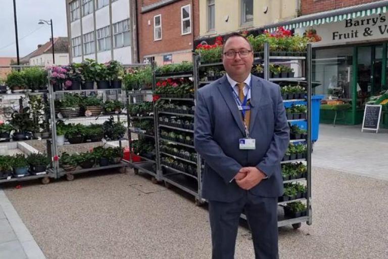 Man in a smart suit standing outside of shops on a high street