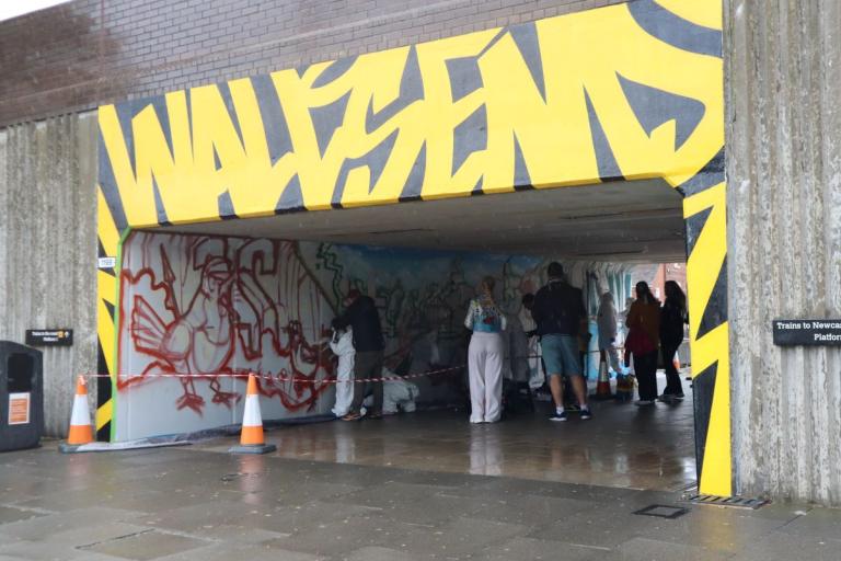 A mural on the Metro underpass with the word Wallsend in graphic yellow letters 