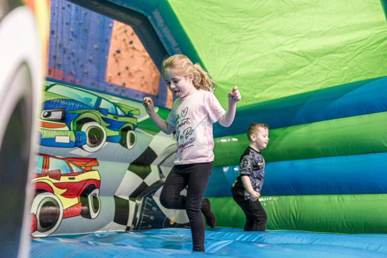 Children bouncing on a green and blue bouncy castle