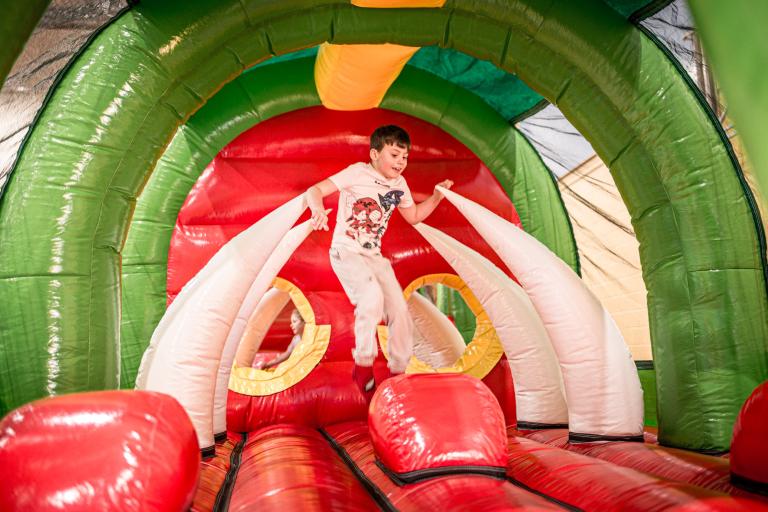 boy on a bouncy castle made to look like a monster's mouth with teeth rising from the ground