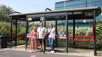 Three people standing in front of a bus stop