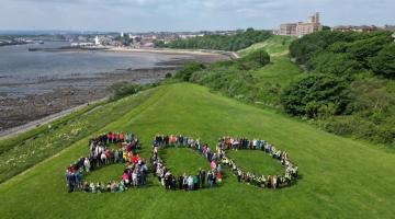 People from North Shields standing in the shape of a number 800 with the Fish Quay behind 