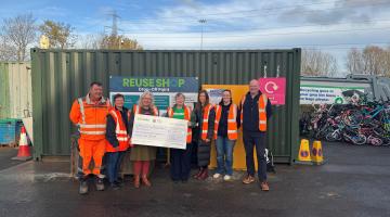 Group of people with charity cheque outside reuse container at North Tyneside HWRC