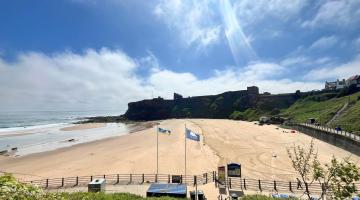 Beach in North Tyneside with two blue flags in the foreground