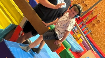 Child supported by a member of staff at a soft play centre. 