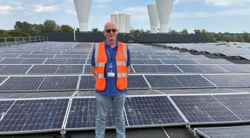 Man with hi-vis vest stood in front of solar panels