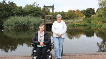 Two female volunteers pictured at the centre of Chirton Dene park in front of the lake 