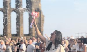 A pink, Unicorn Bubble Machine in action, with Tynemouth Priory in the backround