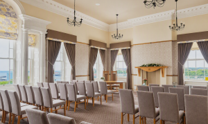 A bright room with rows of chairs set up for a wedding