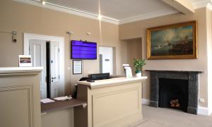 A reception room with a light coloured desk and fireplace