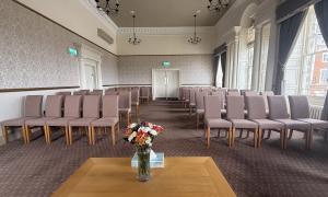 A room with a table in the foreground set up for a wedding
