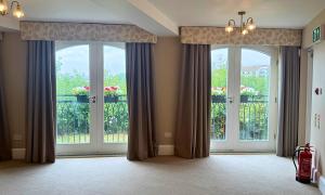 Two large windows with neutral coloured curtains