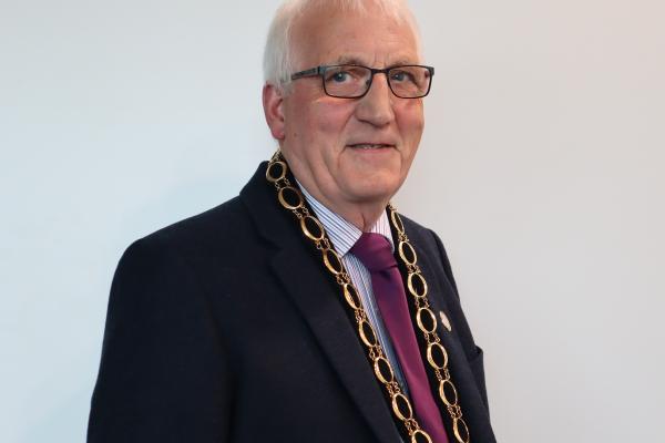 Image of Nigel Huscroft. Man with grey hair and glasses wearing a suit and a large gold ceremonial chain