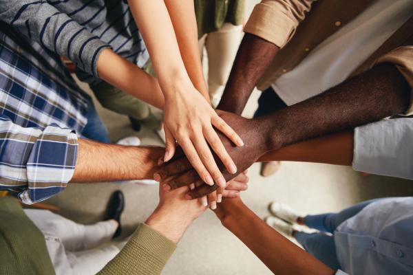 a diverse group of colleagues putting their hands in the middle on top of each other.