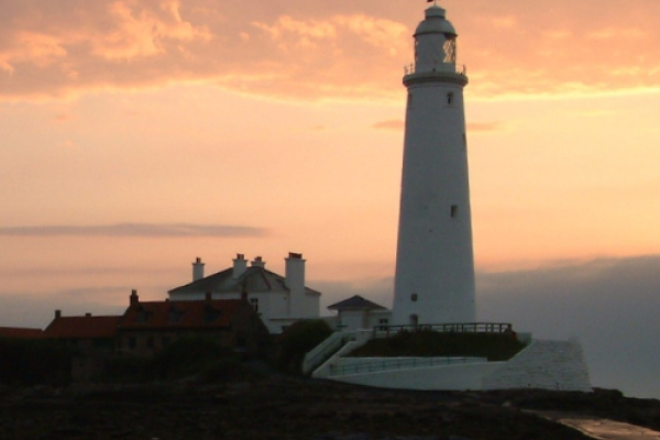 St Mary's Lighthouse and Island shown from afar at sunset and clouds in the sky