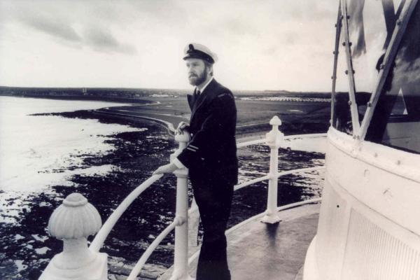 A lighthouse keeper looking out at sea from the lighthouse