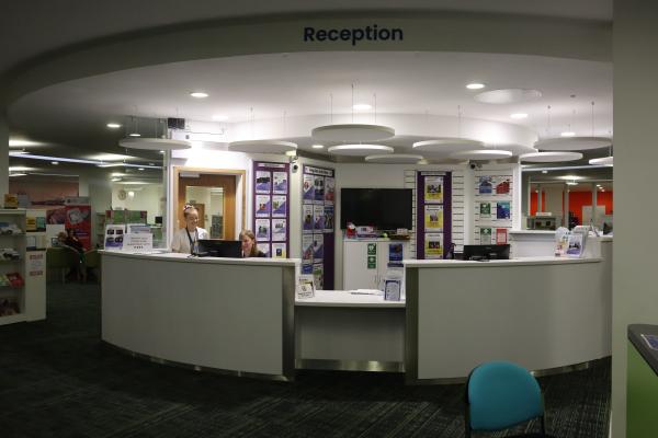 Main desk at a library with a counter that has a lowered space for wheelchairs