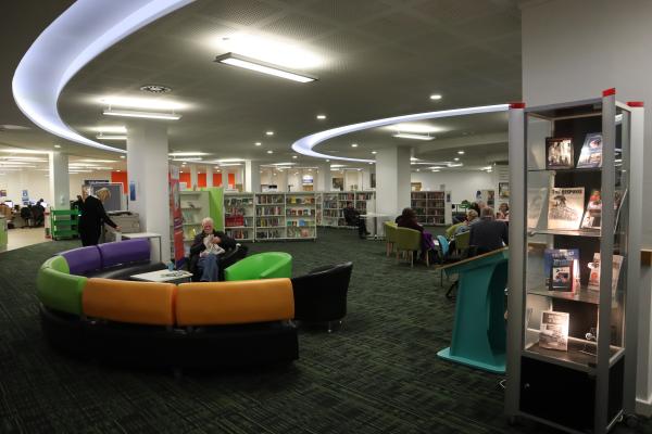 open space in a library with areas to sit. there are tables and chairs