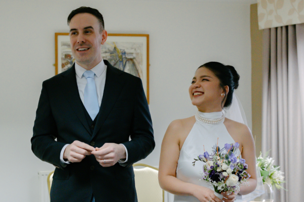 A bride and groom stand side by side with the bride looking up at the groom